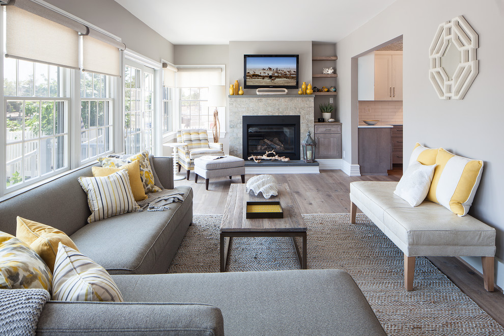 Cette image montre un salon gris et jaune design avec un mur gris, un sol en bois brun, une cheminée standard et un téléviseur fixé au mur.