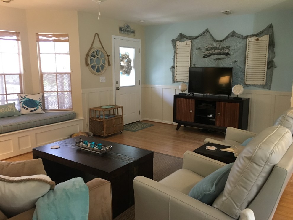 На фото: открытая гостиная комната среднего размера в морском стиле с синими стенами, светлым паркетным полом и отдельно стоящим телевизором