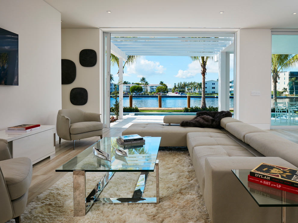 Large modern formal open plan living room in Miami with beige walls, light hardwood flooring, no fireplace and a wall mounted tv.