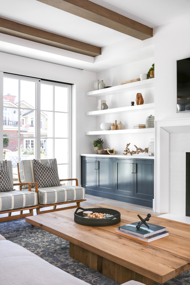 Large minimalist open concept medium tone wood floor and brown floor living room photo in Orange County with white walls, a standard fireplace, a tile fireplace and a wall-mounted tv