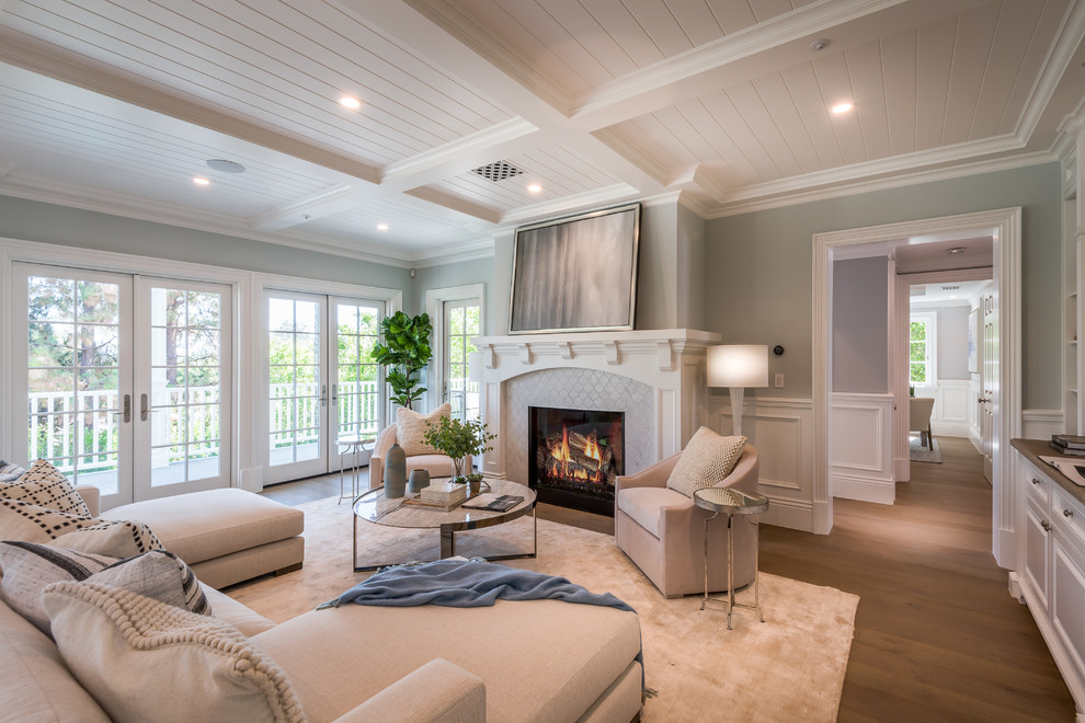 Design ideas for a classic enclosed living room in Los Angeles with grey walls, medium hardwood flooring, a standard fireplace, a tiled fireplace surround, brown floors and feature lighting.