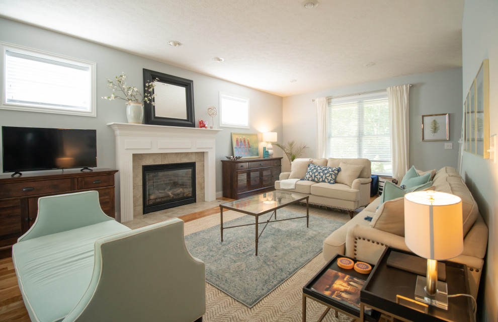 インディアナポリスにある低価格の広いトラディショナルスタイルのおしゃれなLDK (青い壁、無垢フローリング、標準型暖炉、木材の暖炉まわり、据え置き型テレビ、オレンジの床) の写真
