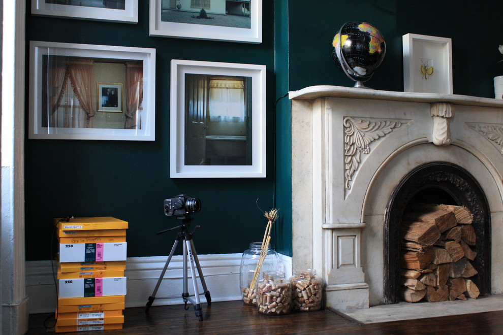 Cette photo montre un salon éclectique de taille moyenne avec un sol en bois brun, une cheminée standard, un manteau de cheminée en pierre et un mur vert.