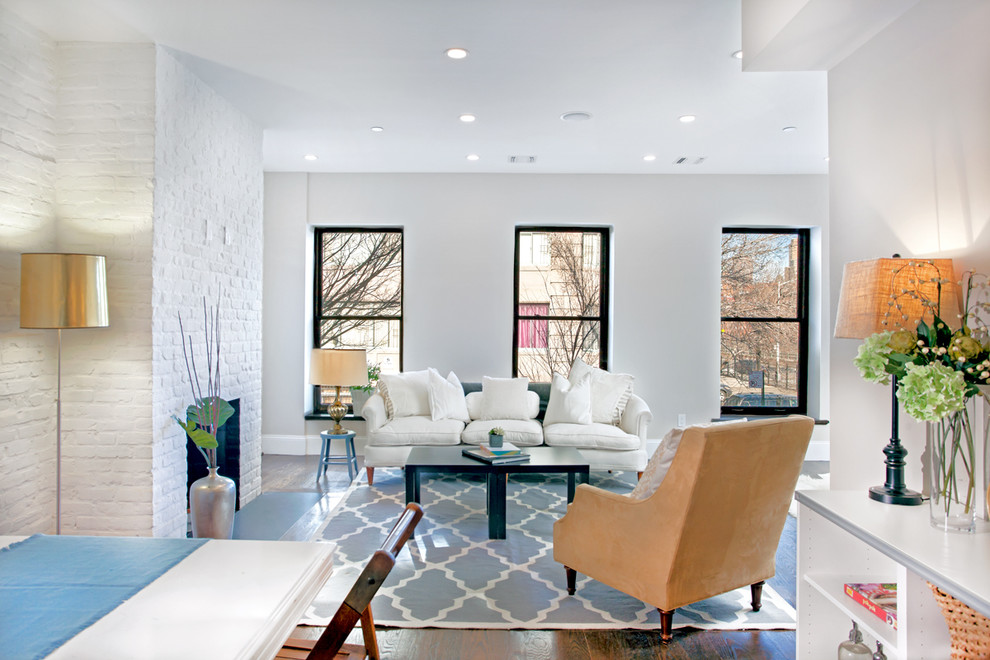 Example of a mid-sized classic formal and open concept medium tone wood floor and brown floor living room design in New York with white walls, a standard fireplace, a brick fireplace and no tv
