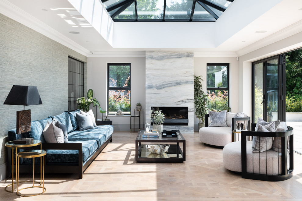 Design ideas for an expansive contemporary formal open plan living room in Surrey with a standard fireplace, white walls, no tv, light hardwood flooring and a stone fireplace surround.