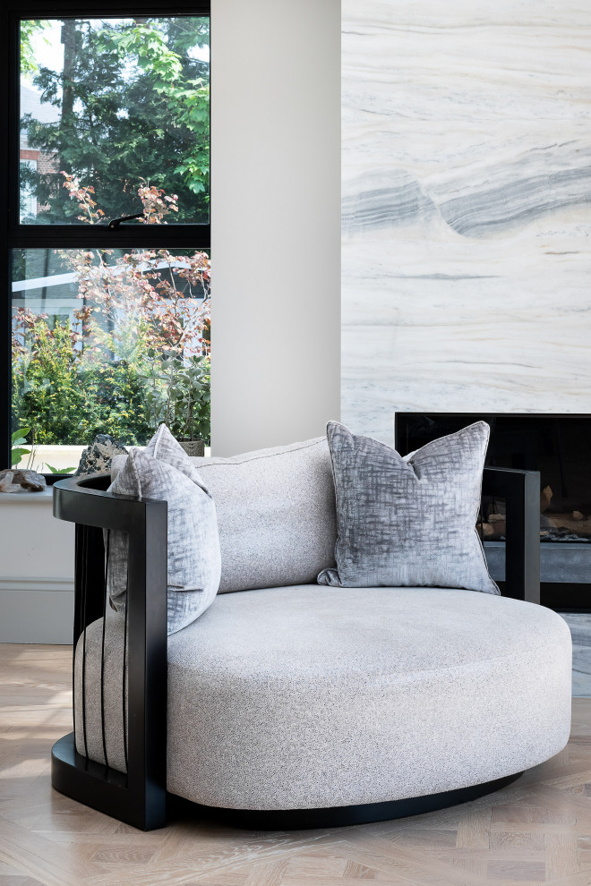 Inspiration for a contemporary living room in Surrey with light hardwood flooring, a standard fireplace and a stone fireplace surround.