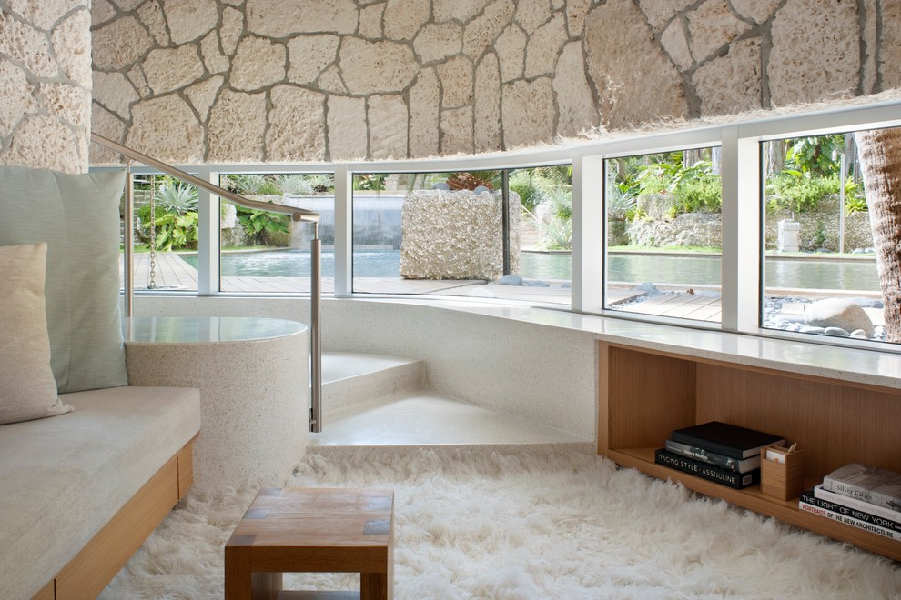 Imagen de biblioteca en casa cerrada tropical de tamaño medio sin chimenea y televisor con paredes blancas y piedra