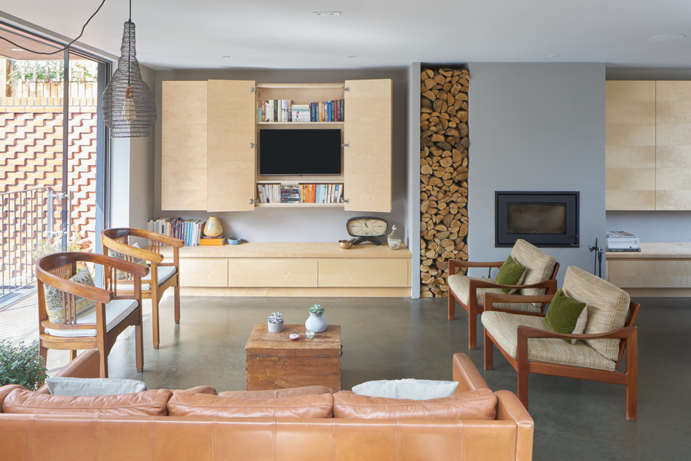 Esempio di un grande soggiorno moderno aperto con pareti grigie, pavimento in cemento, stufa a legna, cornice del camino in intonaco e parete attrezzata