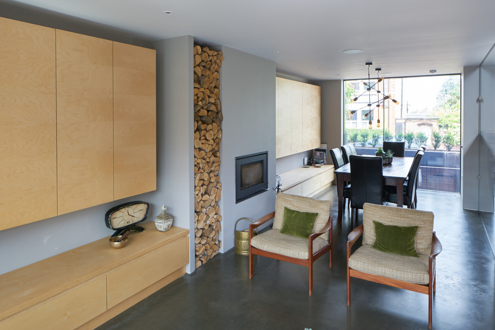 Foto di un grande soggiorno minimalista aperto con pareti grigie, pavimento in cemento, stufa a legna, cornice del camino in intonaco e parete attrezzata