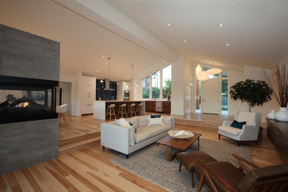 Источник вдохновения для домашнего уюта: большая открытая гостиная комната в современном стиле с белыми стенами, светлым паркетным полом, двусторонним камином, фасадом камина из бетона и коричневым полом