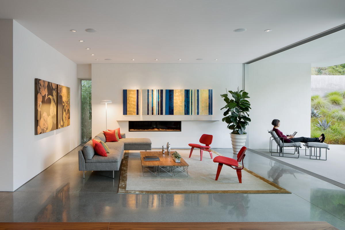 Imagen de salón abierto minimalista de tamaño medio sin televisor con chimenea lineal, paredes blancas, suelo de cemento, marco de chimenea de yeso y suelo gris