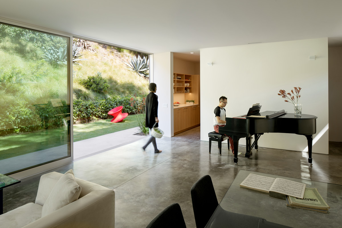 Diseño de salón abierto moderno con paredes blancas y suelo de cemento