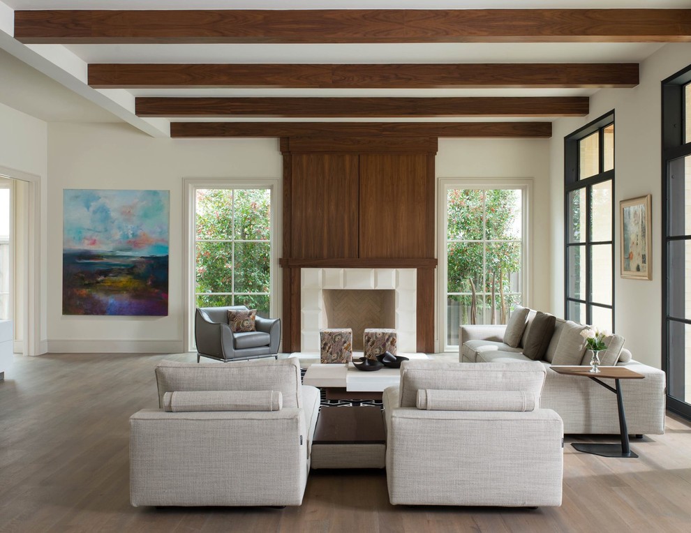 Repräsentatives Modernes Wohnzimmer mit weißer Wandfarbe, hellem Holzboden, Kamin, gefliester Kaminumrandung und verstecktem TV in Dallas