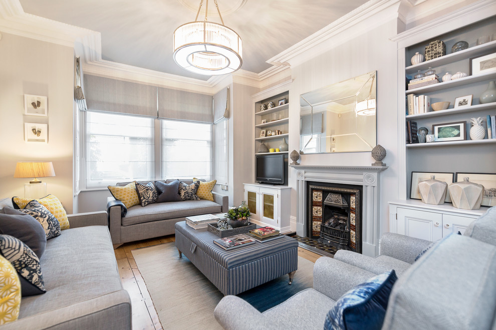 Abgetrenntes Klassisches Wohnzimmer mit grauer Wandfarbe, braunem Holzboden, Kaminofen, gefliester Kaminumrandung und freistehendem TV in London