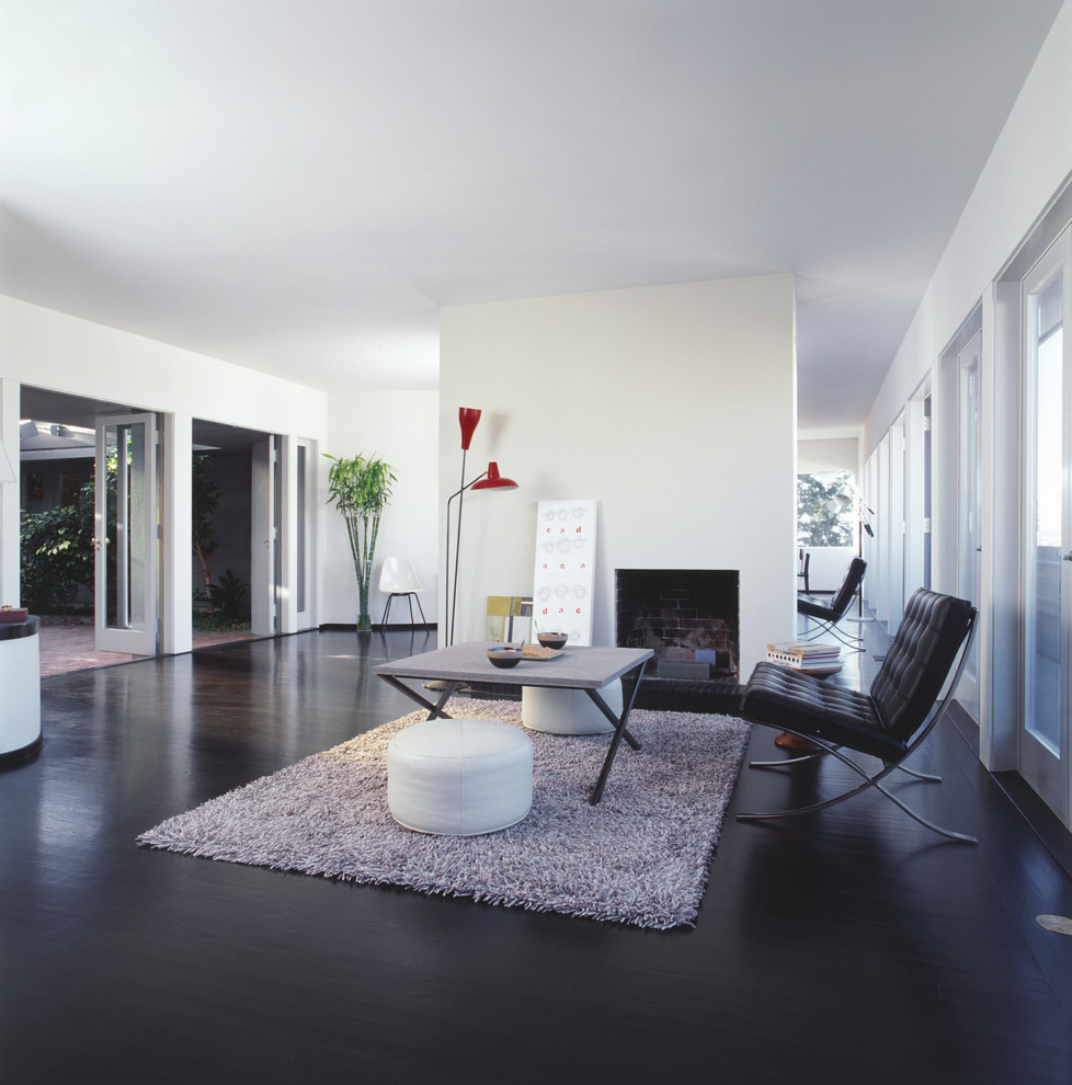 Стильный дизайн: гостиная комната в стиле модернизм с белыми стенами и черным полом - последний тренд