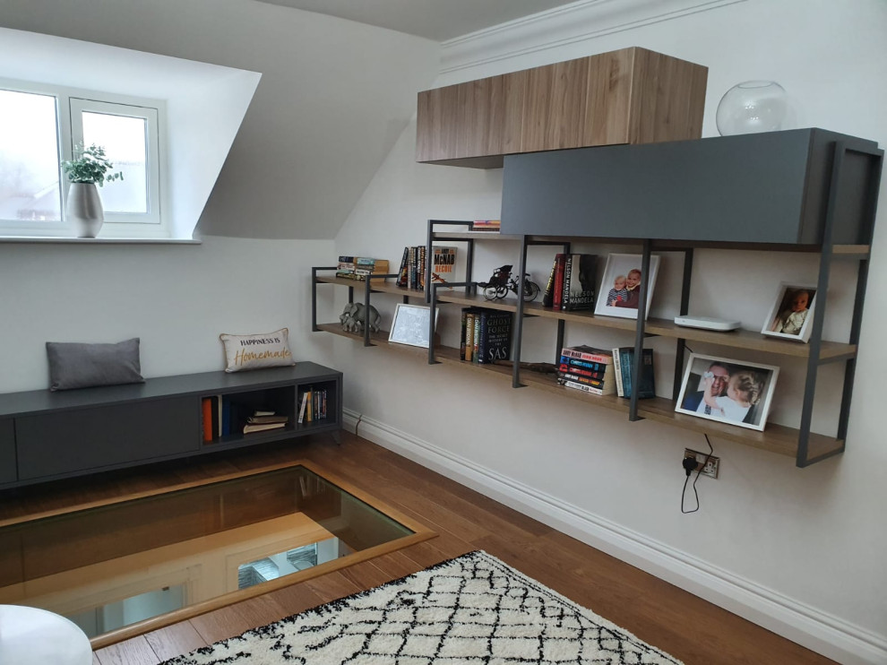 Immagine di un piccolo soggiorno scandinavo stile loft con libreria, pareti bianche, parquet chiaro, nessun camino, nessuna TV e pavimento marrone