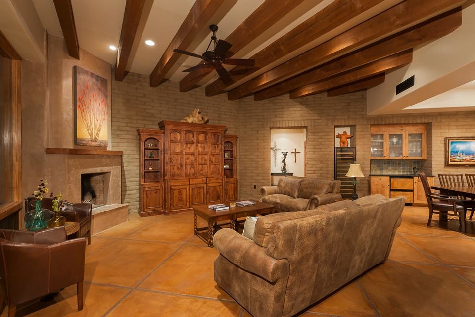 This is an example of a large traditional open plan living room in Phoenix with beige walls, concrete flooring, a corner fireplace, a plastered fireplace surround, a concealed tv and a home bar.