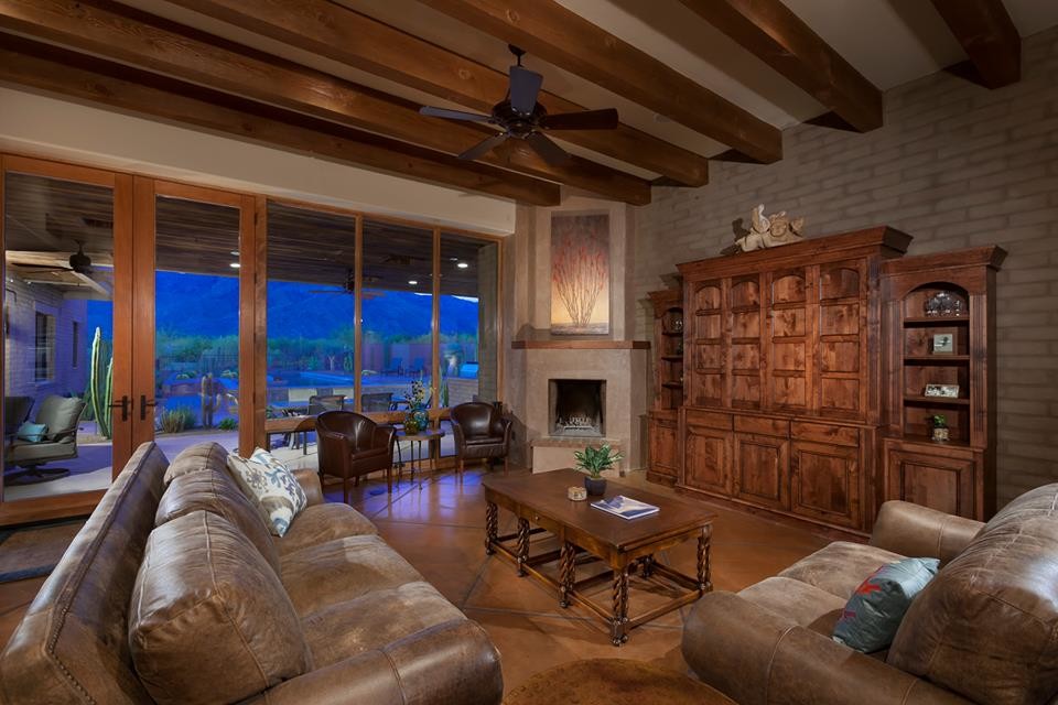 フェニックスにあるラグジュアリーな広いトラディショナルスタイルのおしゃれなLDK (ベージュの壁、コンクリートの床、コーナー設置型暖炉、漆喰の暖炉まわり、内蔵型テレビ) の写真