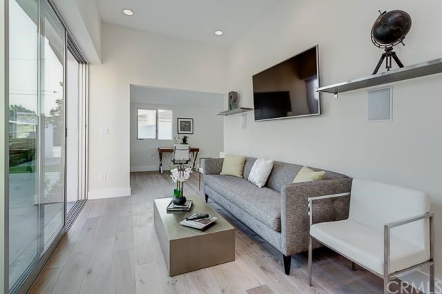 Esempio di un piccolo soggiorno moderno aperto con parquet chiaro, camino classico, TV a parete e pareti bianche