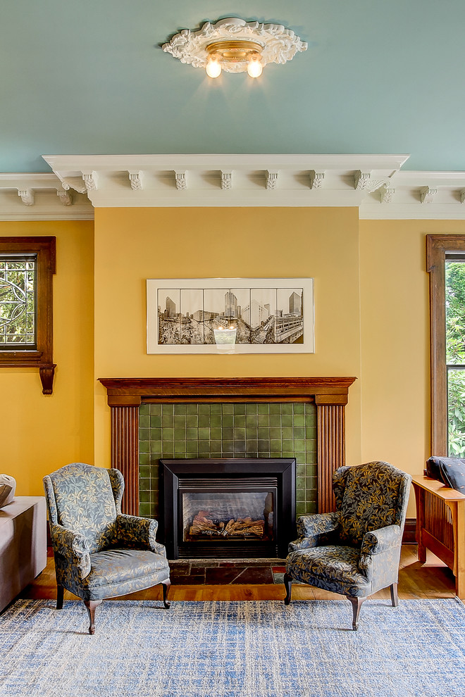 Aménagement d'un très grand salon classique fermé avec une salle de réception, un mur jaune, un sol en bois brun, une cheminée standard, un manteau de cheminée en carrelage et aucun téléviseur.