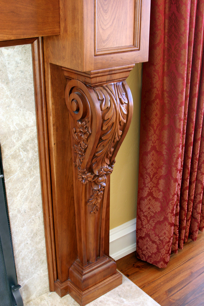 Cette image montre un grand salon traditionnel avec un mur beige, un sol en bois brun, une cheminée standard et un manteau de cheminée en pierre.