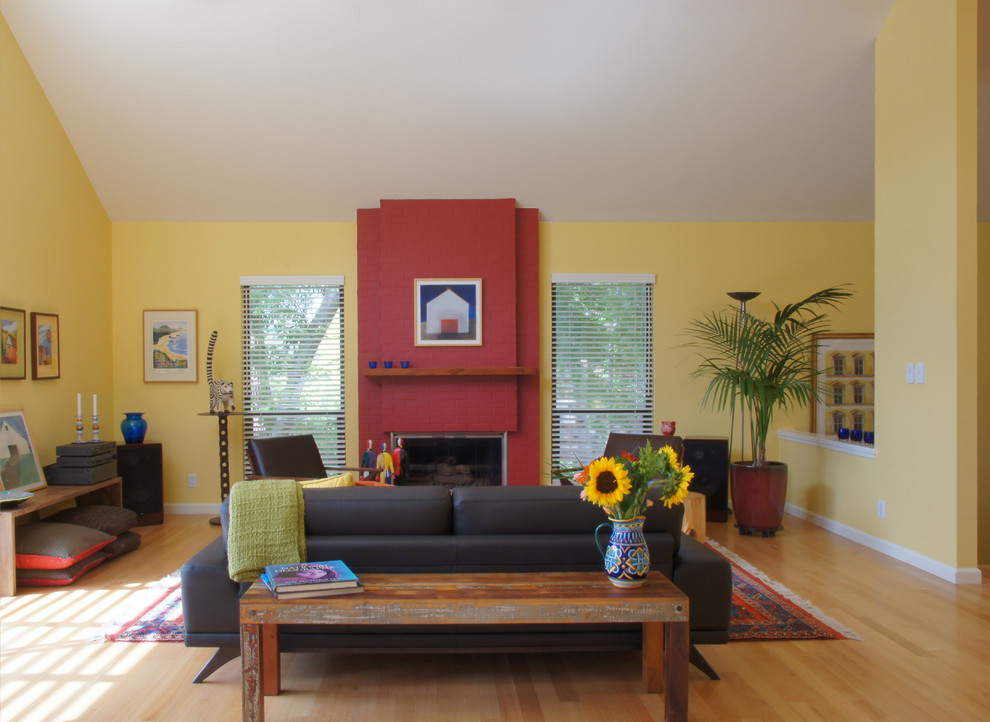 Mittelgroßes, Fernseherloses Stilmix Wohnzimmer im Loft-Stil mit gelber Wandfarbe, hellem Holzboden, Kamin und Kaminumrandung aus Backstein in San Francisco