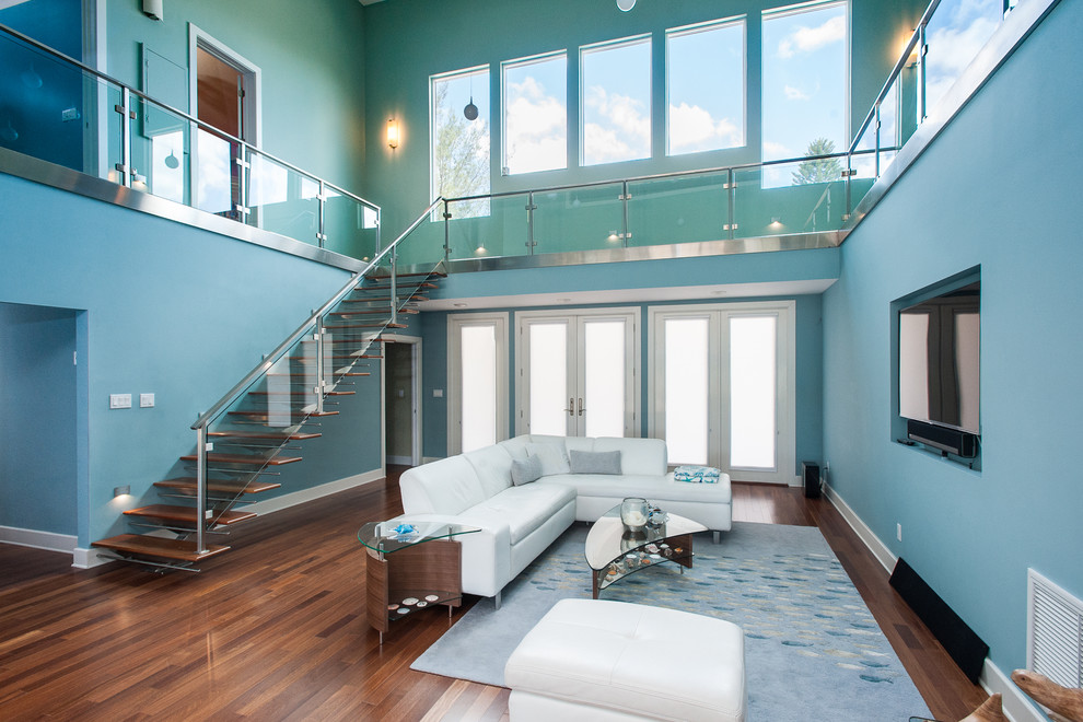 Foto di un grande soggiorno design aperto con pareti blu, pavimento in legno massello medio, nessun camino, TV a parete e pavimento marrone