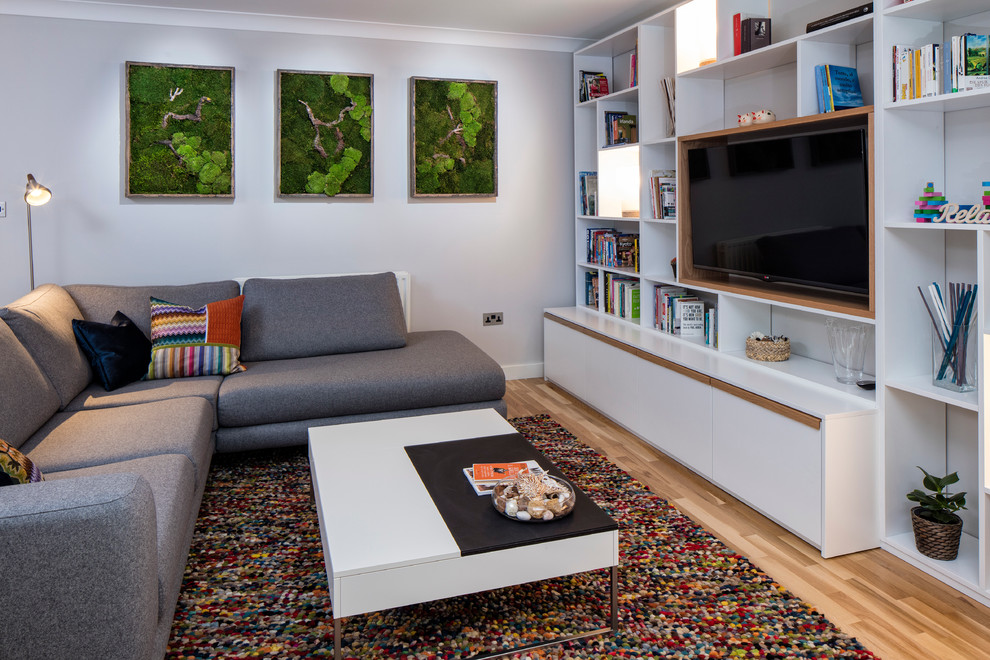 Foto di un soggiorno minimalista di medie dimensioni e aperto con pareti grigie, pavimento in legno massello medio e TV a parete