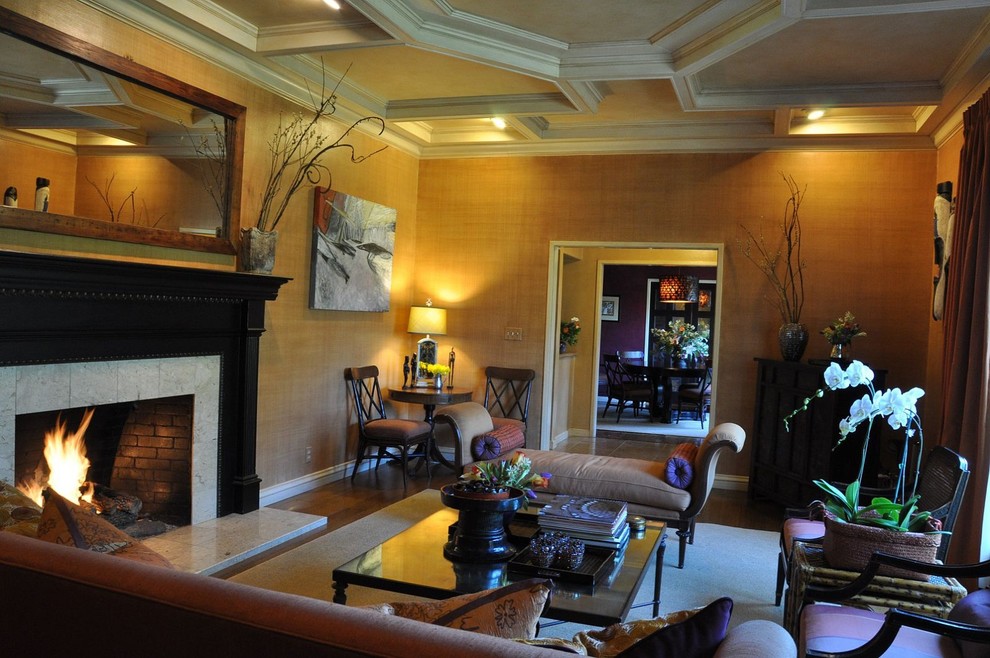 Cette image montre un grand salon bohème ouvert avec une salle de réception, un mur orange, un sol en bois brun, un manteau de cheminée en carrelage et aucun téléviseur.