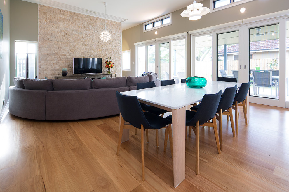 Modelo de salón abierto contemporáneo de tamaño medio sin chimenea con paredes verdes, suelo de madera en tonos medios y televisor independiente