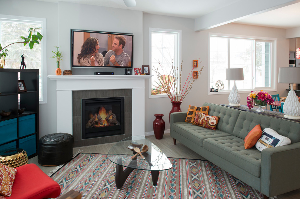 Стильный дизайн: открытая гостиная комната в стиле неоклассика (современная классика) с серыми стенами, стандартным камином, фасадом камина из плитки, телевизором на стене и серым полом - последний тренд