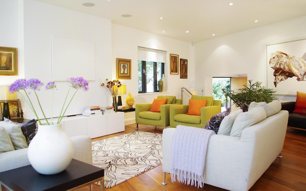 Huge minimalist open concept medium tone wood floor living room photo in London with a concealed tv and white walls