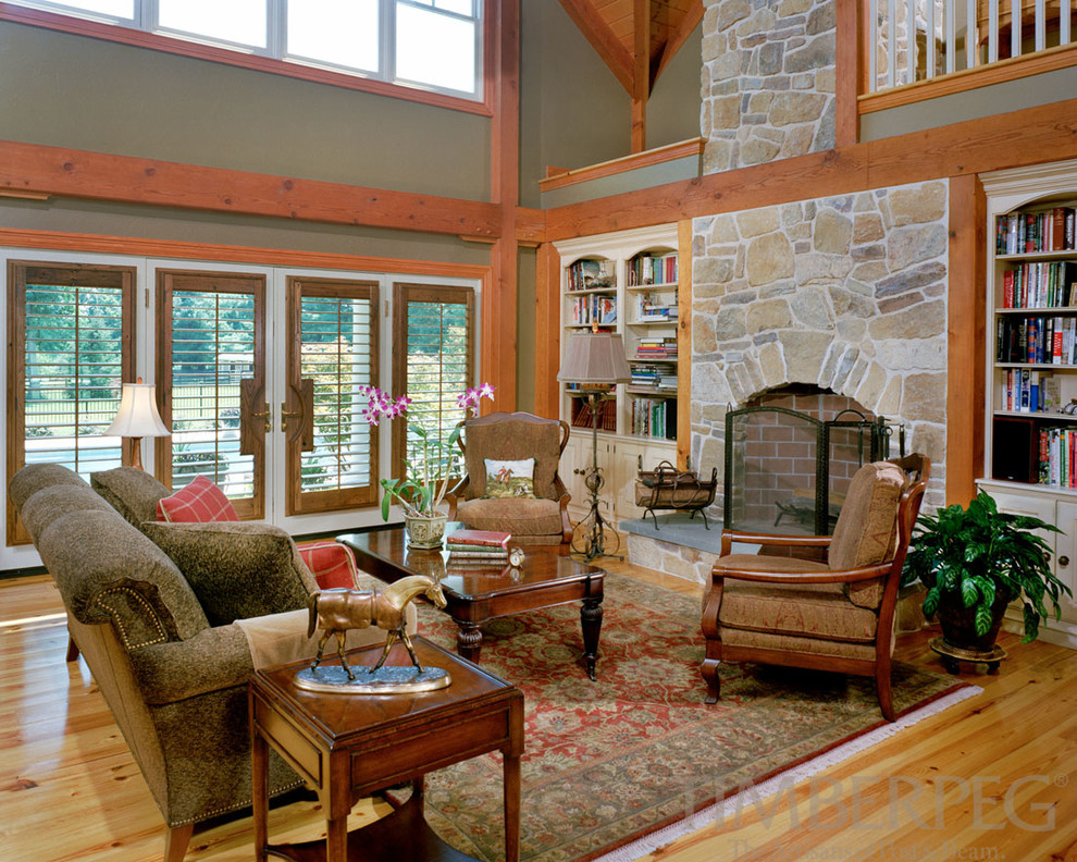 Imagen de salón abierto campestre con paredes verdes, suelo de madera en tonos medios, todas las chimeneas y marco de chimenea de piedra