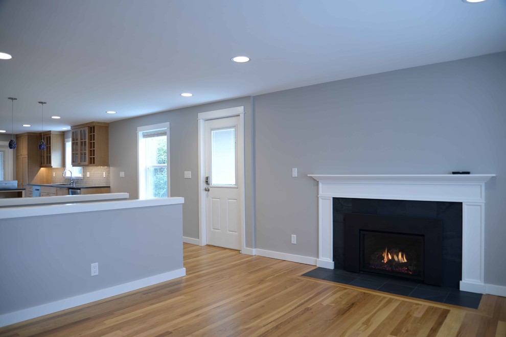 Пример оригинального дизайна: гостиная комната среднего размера в стиле кантри с серыми стенами, светлым паркетным полом, стандартным камином и фасадом камина из дерева