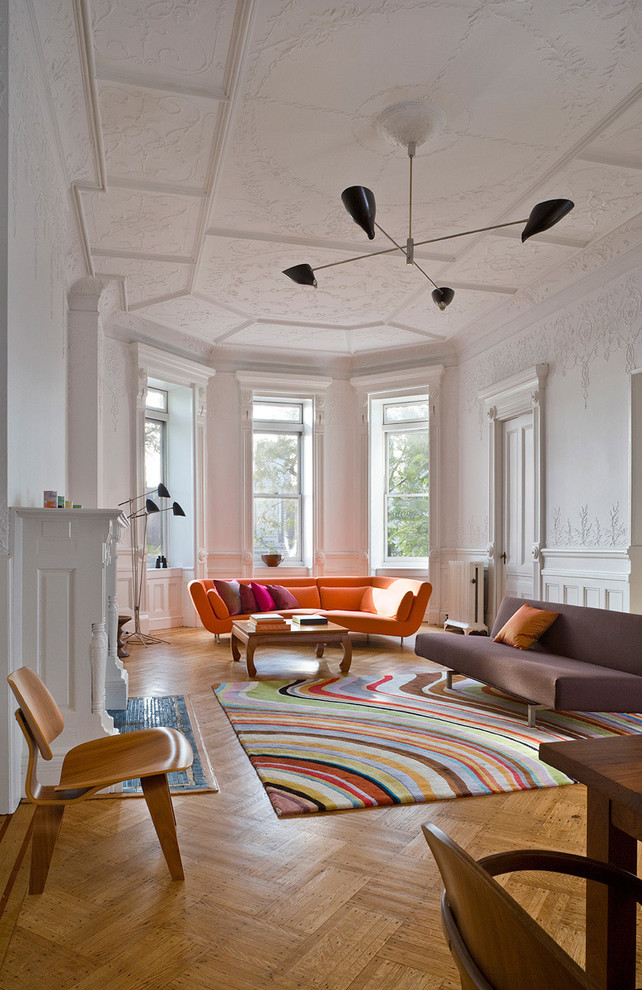 Пример оригинального дизайна: гостиная комната в стиле ретро с белыми стенами и коричневым диваном