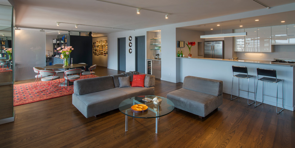 Exemple d'un grand salon tendance ouvert avec une bibliothèque ou un coin lecture, un mur gris et un sol en bois brun.