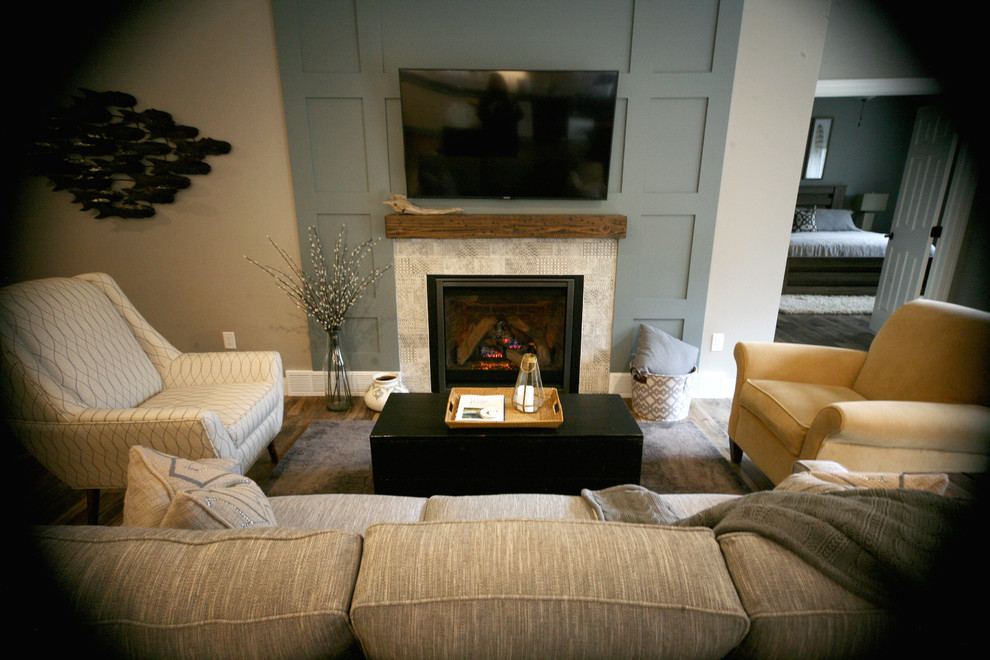 На фото: открытая, парадная гостиная комната среднего размера в стиле фьюжн с серыми стенами, полом из винила, стандартным камином, фасадом камина из плитки и телевизором на стене