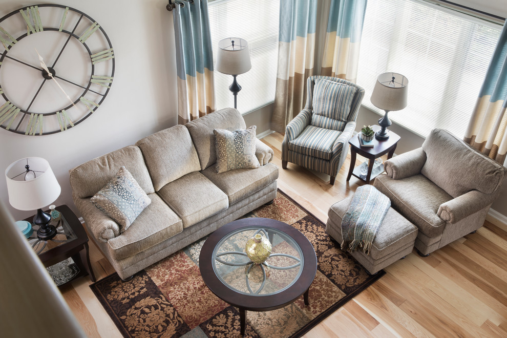 Foto di un soggiorno chic di medie dimensioni con pareti beige, parquet chiaro, camino classico, cornice del camino in mattoni e nessuna TV