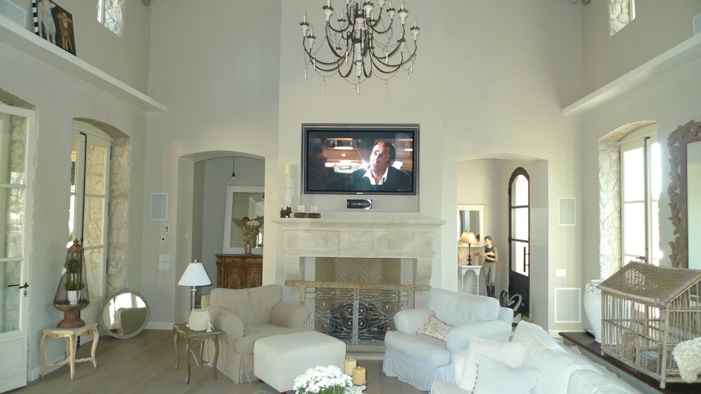 Стильный дизайн: открытая гостиная комната среднего размера в стиле шебби-шик с белыми стенами, светлым паркетным полом, стандартным камином, фасадом камина из камня и телевизором на стене - последний тренд