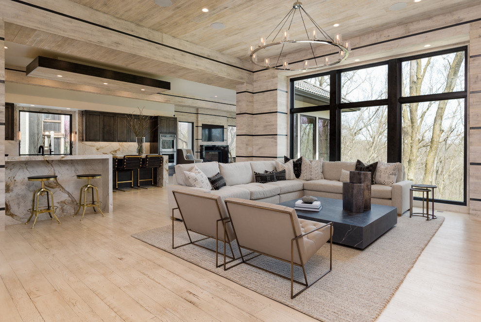 Large modern open plan living room in Kansas City with beige walls, light hardwood flooring and a two-sided fireplace.