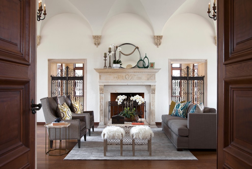 Mediterranean living room in Austin with white walls, dark hardwood flooring and a standard fireplace.