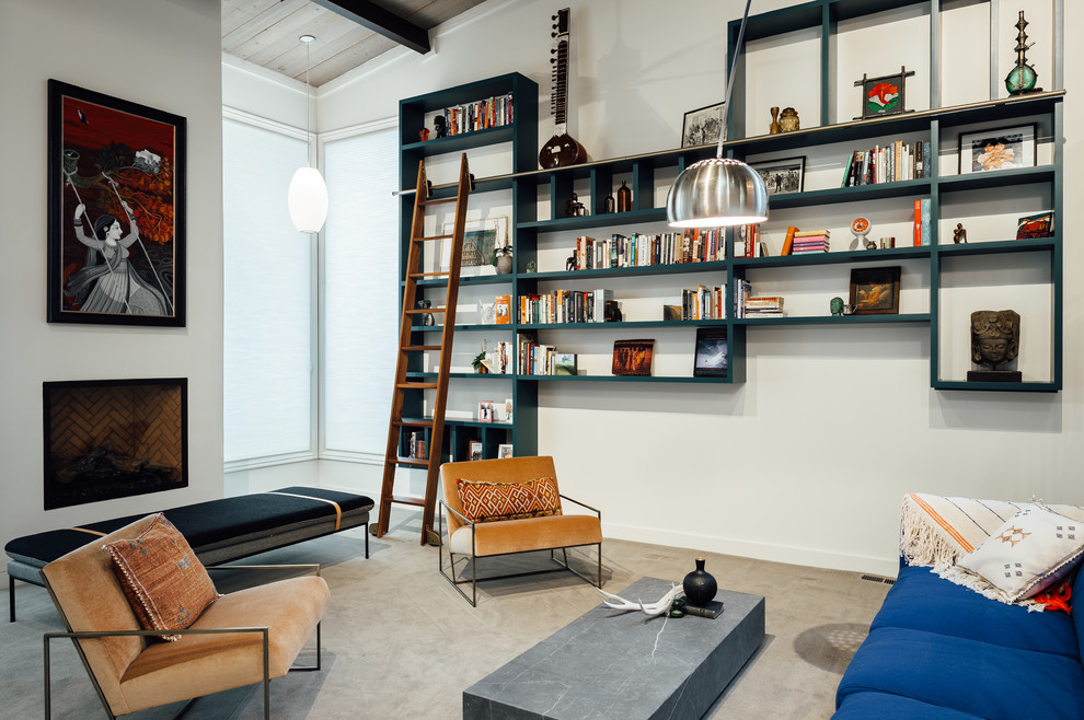 Immagine di un soggiorno moderno di medie dimensioni e stile loft con libreria, pareti bianche, moquette, camino classico, cornice del camino in intonaco e pavimento beige