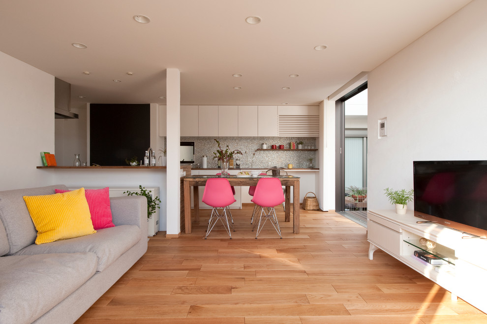Imagen de salón abierto actual con paredes blancas, suelo de madera en tonos medios y televisor independiente