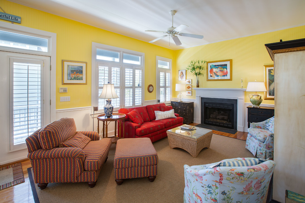 チャールストンにある中くらいなトラディショナルスタイルのおしゃれなLDK (黄色い壁、無垢フローリング、標準型暖炉、木材の暖炉まわり、内蔵型テレビ、茶色い床) の写真