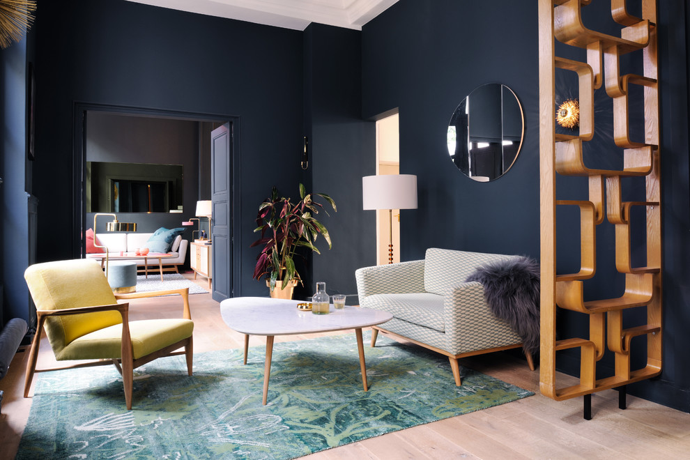 Photo of a contemporary formal living room in London with light hardwood flooring, blue walls and feature lighting.