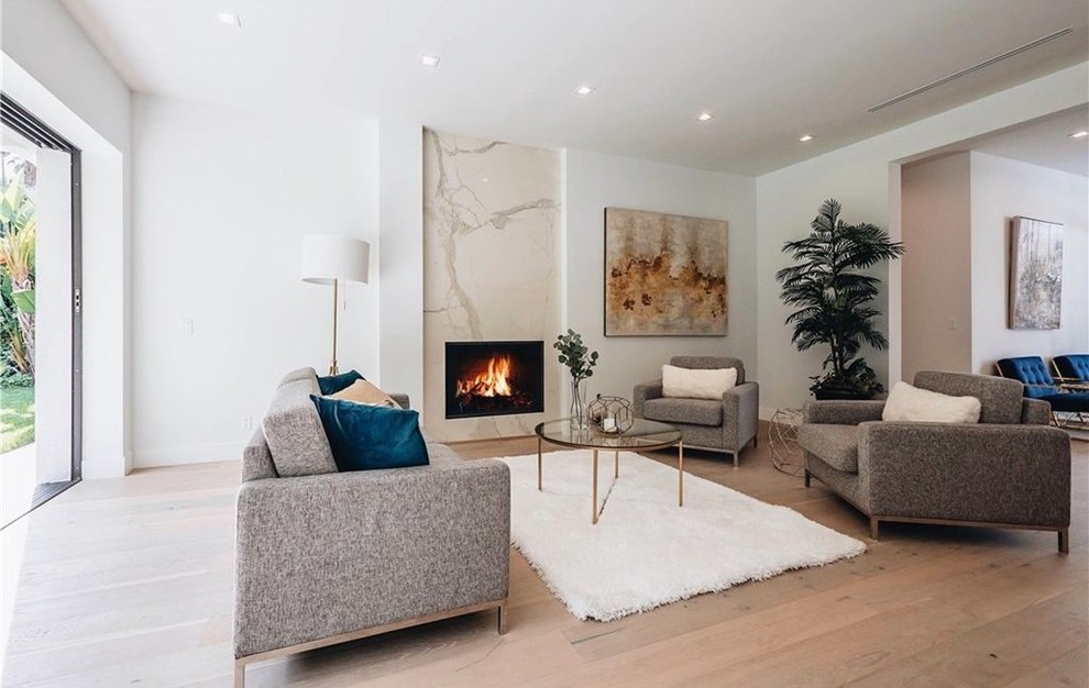 This is an example of an expansive modern formal open plan living room in San Francisco with white walls, light hardwood flooring, a ribbon fireplace, a stone fireplace surround, no tv and beige floors.