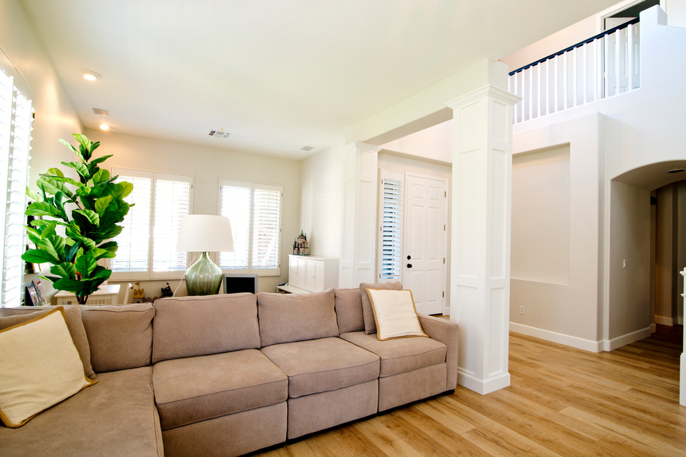 Ejemplo de salón abierto de estilo de casa de campo grande con paredes blancas, suelo laminado y suelo marrón