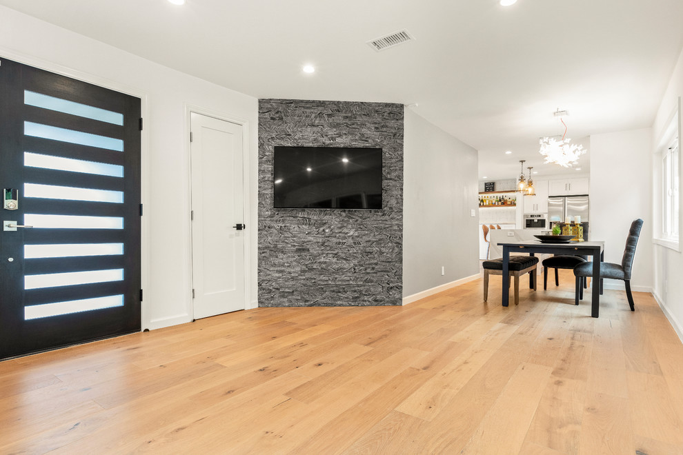 ロサンゼルスにある中くらいなトランジショナルスタイルのおしゃれなLDK (グレーの壁、淡色無垢フローリング、暖炉なし、壁掛け型テレビ、茶色い床) の写真
