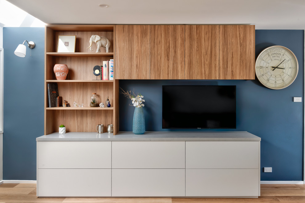 Стильный дизайн: гостиная комната в современном стиле с синими стенами, паркетным полом среднего тона, телевизором на стене и коричневым полом - последний тренд