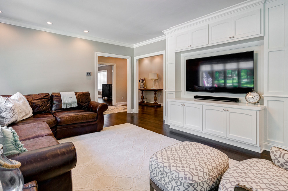 На фото: большая изолированная гостиная комната в стиле неоклассика (современная классика) с серыми стенами, телевизором на стене и паркетным полом среднего тона без камина